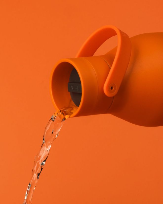 orange stainless steel water bottle pouring
